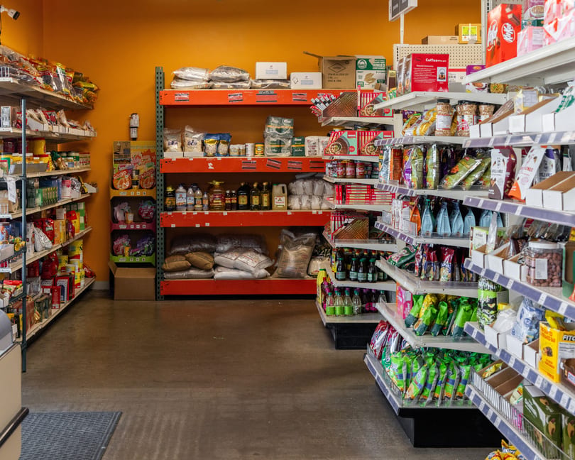 A grocery store aisle with shelves stocked with various packaged foods, spices, and beverages.