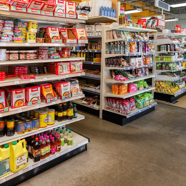 A grocery store aisle filled with shelves of various packaged foods, oils, and spices.