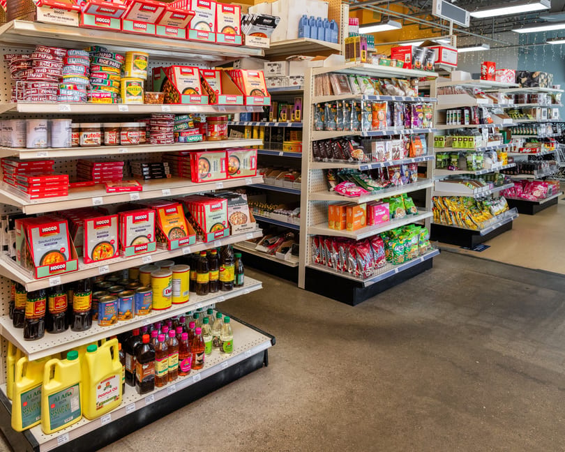 A grocery store aisle filled with shelves of various packaged foods, oils, and spices.