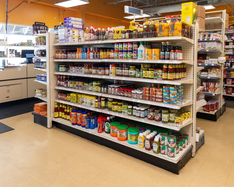 A grocery store aisle filled with shelves of various food products, sauces, and canned goods.